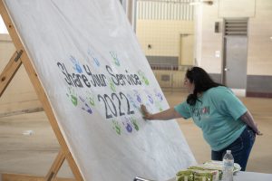 An Aggie mom placing her handprint on the Share Your Service 2022 banner.